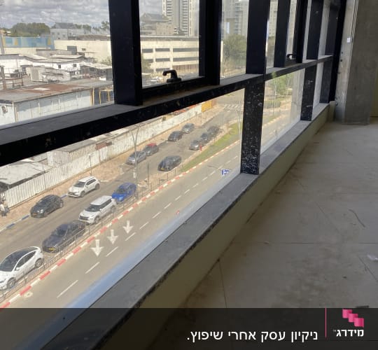חלון גדול עם סימני לכלוך, נוף עירוני בחוץ